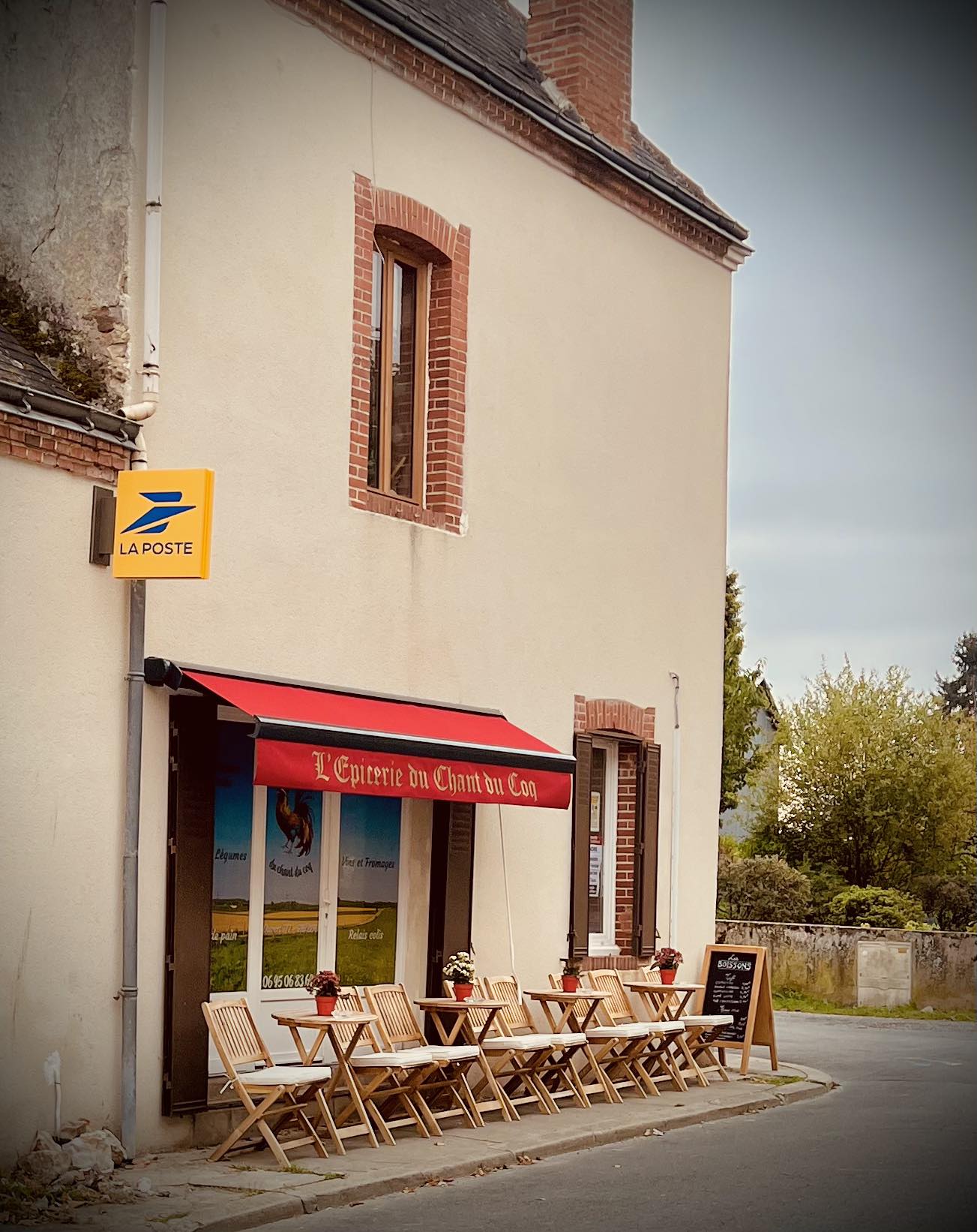 Façade de L'Auberge du Chant du Coq, auvent rouge, terrasse