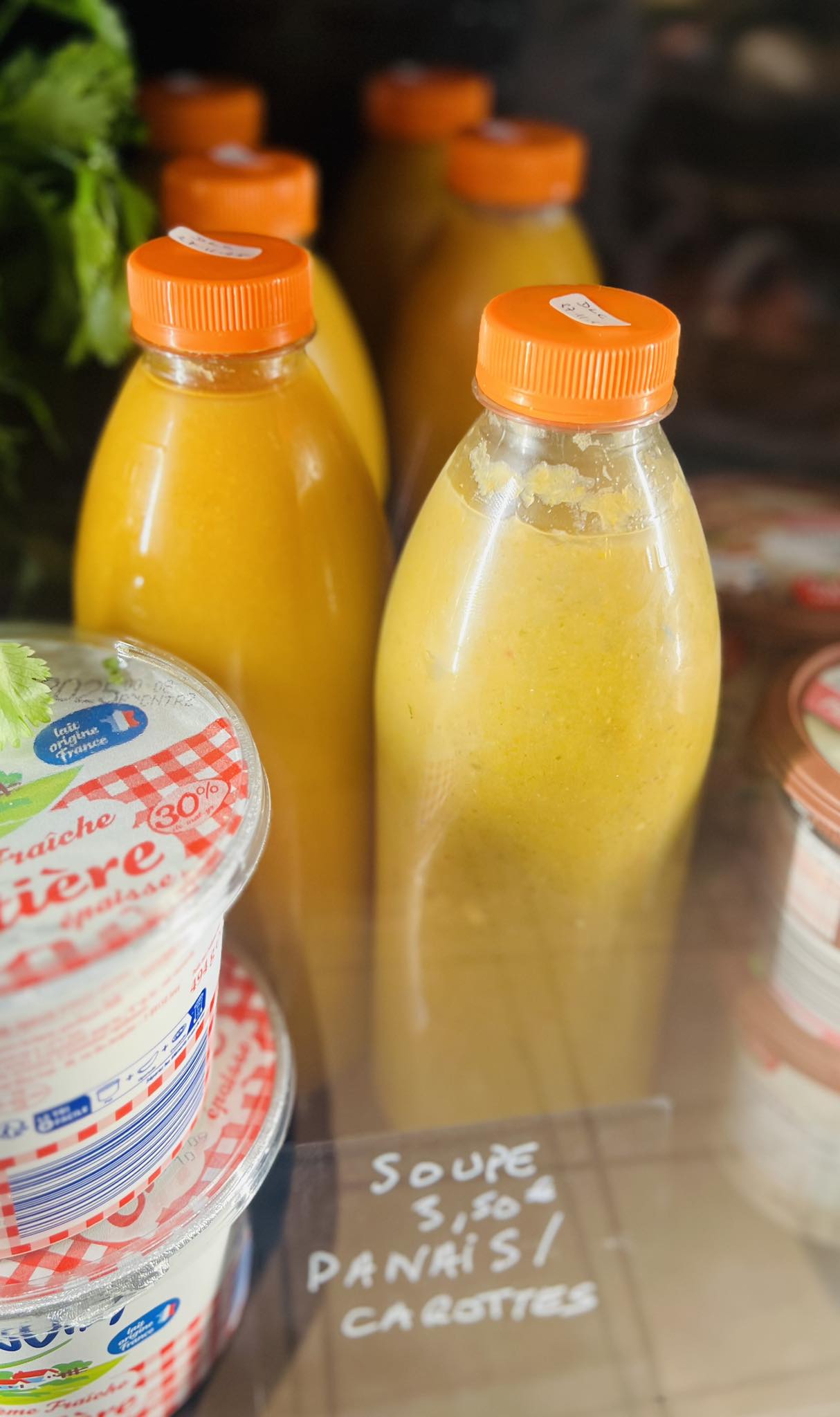 Bouteilles de soupe panais-carottes 3,50€ et crème fraîche dans la vitrine réfrigérée